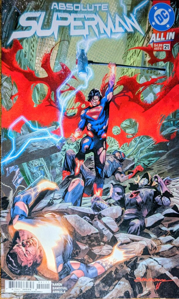 Absolute Superman #21 comic book cover depicting a battered Absolute Superman holding Henry Iron's hammer over his head with blue lightening and red dust cape. Henry Irons, Absolute Hawkman, and King Shazam lay in the rubble.